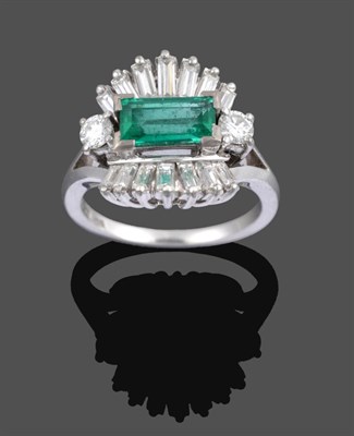 Lot 1075 - An Emerald and Diamond Cluster Ring, the central step cut emerald flanked by two round...
