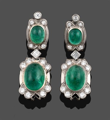 Lot 1079 - A Pair of Emerald and Diamond Drop Earrings, a round brilliant cut diamond surmounts an oval...