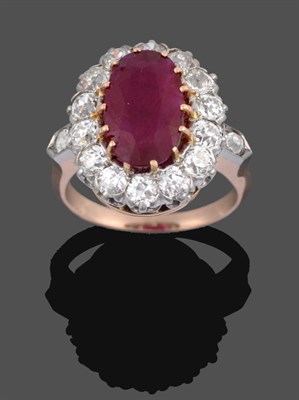 Lot 1082 - A Ruby and Diamond Cluster Ring, the oval cut ruby in a yellow claw setting within a border of...