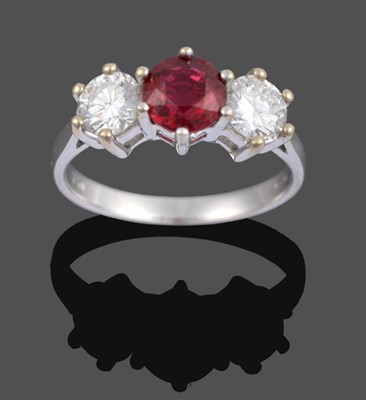 Lot 1085 - An 18 Carat White Gold Ruby and Diamond Three Stone Ring, a round cut ruby sits between two...
