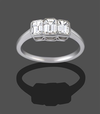 Lot 1119 - A Diamond Three Stone Ring, the graduated emerald-cut diamonds in white millegrain settings, to...