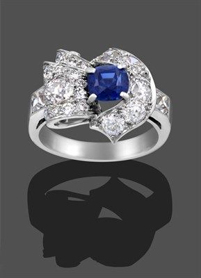 Lot 1134 - A Sapphire and Diamond Cluster Ring, the central round cut sapphire in a white claw setting, within