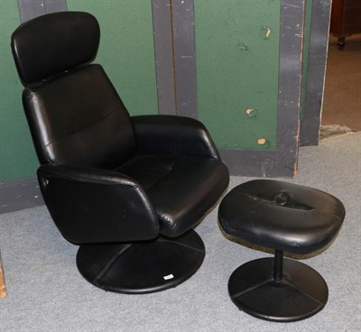Lot 1083 - A modern black swivel chair and footstool
