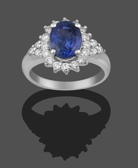 Lot 2004 - A Sapphire and Diamond Cluster Ring, the oval cut sapphire within a border of round brilliant...