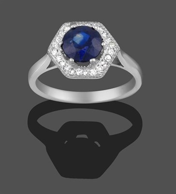 Lot 2005 - A Sapphire and Diamond Cluster Ring, the round cut sapphire in a white four claw setting within...