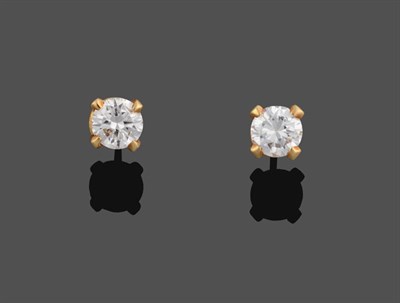 Lot 2030 - A Pair of Diamond Solitaire Earrings, the round brilliant cut diamonds in yellow four claw...