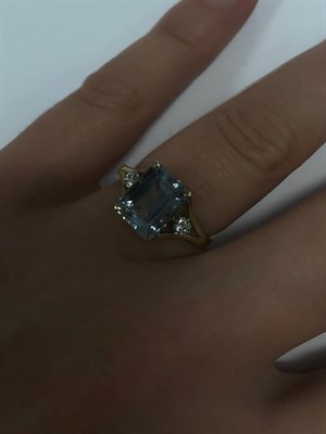 Lot 2034 - An 18 Carat Gold Aquamarine and Diamond Ring, the emerald-cut aquamarine in a yellow claw...