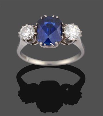 Lot 2072 - A Synthetic Sapphire and Diamond Three Stone Ring, the fancy cushion cut sapphire flanked by...