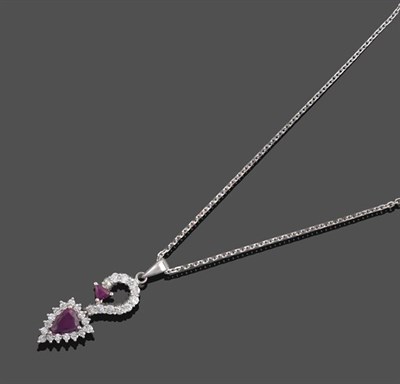 Lot 2104 - A Ruby and Diamond Pendant on An 18 Carat White Gold Chain, a trilliant cut ruby to a swirl...