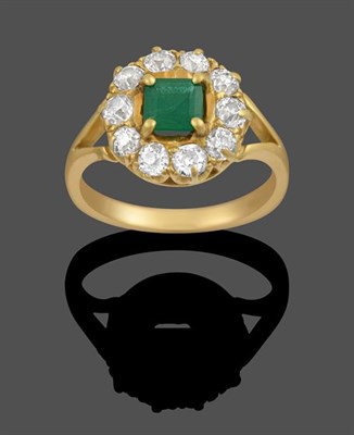 Lot 2124 - An 18 Carat Gold Emerald and Diamond Cluster Ring, the emerald-cut emerald within a border of...