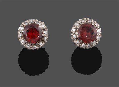 Lot 2135 - A Pair of Garnet and Diamond Cluster Earrings, the round cut garnet within a border of...
