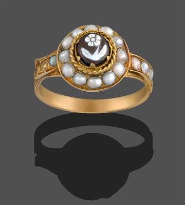 Lot 2139 - An Onyx and Seed Pearl Mourning Ring, the onyx carved to depict a forget-me-not in a yellow...