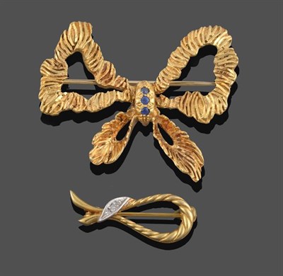 Lot 2200 - A 15 Carat Gold Sapphire Bow Brooch, the yellow textured ribbons gathered centrally by a trio...