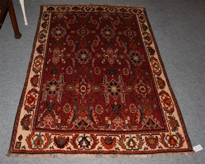 Lot 337 - An Oriental rug, the red field of hooked lozenges and stylised flowers within a geometric...