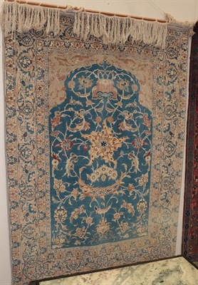 Lot 342 - An Oriental prayer rug, the Mihrab decorated with stylised flowers on a blue ground, within...