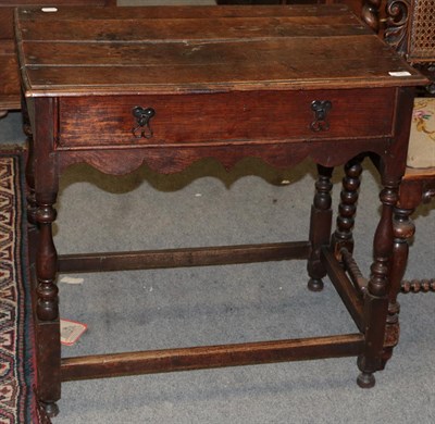 Lot 440 - An early 18th century oak side table with a single drawer, wavy shaped apron and baluster legs,...