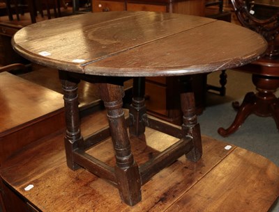 Lot 446 - An early 19th century provincial oak drop-leaf table, raised on turned legs with block feet,...