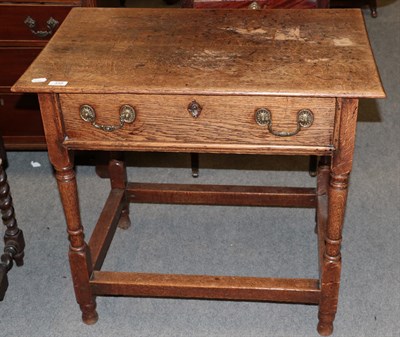 Lot 448 - An 18th century oak side table, fitted with a drawer, raised on turned and block legs joined by...