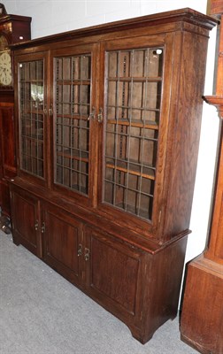 Lot 510 - A 20th century leaded and glazed three door oak bookcase, 185cm high by 171cm wide by 39cm deep