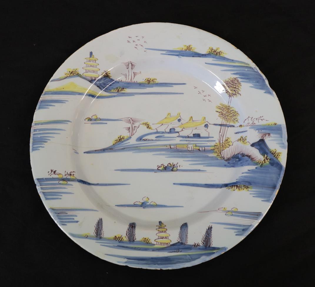 Lot 25 - An English Delft Plate, mid 18th century, painted in blue, yellow and manganese with a river...