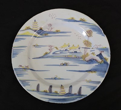 Lot 25 - An English Delft Plate, mid 18th century, painted in blue, yellow and manganese with a river...