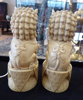 Lot 116 - A Pair of Chinese Carved Ivory Dogs of Fo, 19th century, of traditional form, sitting on oval...