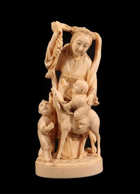 Lot 134 - A Japanese Ivory Okimono of a Maiden, Meiji period, standing holding a bunch of grapes, a child...