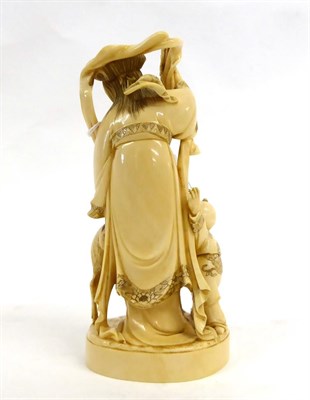 Lot 134 - A Japanese Ivory Okimono of a Maiden, Meiji period, standing holding a bunch of grapes, a child...