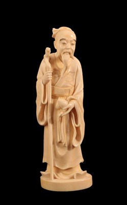 Lot 135 - A Japanese Ivory Okimono of a Sage, Meiji period, standing in flowing robes holding a peach and...