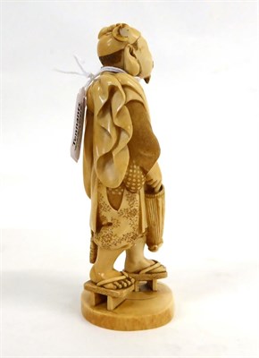 Lot 139 - A Japanese Ivory Okimono as a Fisherman, Meiji period, standing holding a rod, basket and umbrella