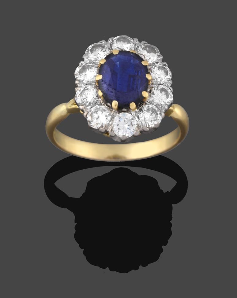 Lot 234 - A Sapphire and Diamond Cluster Ring, the oval cut sapphire in a yellow claw setting, within a...