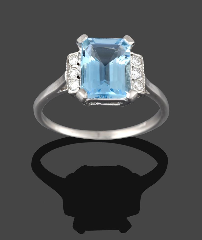Lot 244 - An Aquamarine and Diamond Ring, the emerald-cut aquamarine in white claw settings, flanked by trios