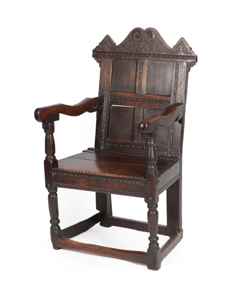 Lot 573 - A 17th Century Joined Oak Wainscot Armchair, the scrolled top rail carved with fleur de lys scrolls