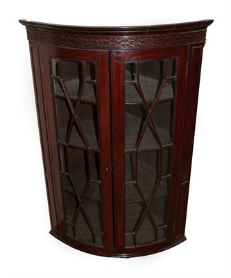 Lot 655 - An Early 19th Century Mahogany Bowfront Hanging Corner Cupboard, with dentil cornice above a...