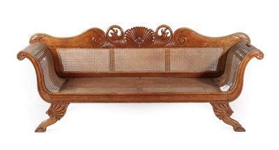 Lot 746 - A Regency Hardwood Carved and Caned Scroll End Sofa, West Indies, the back support centred by C...