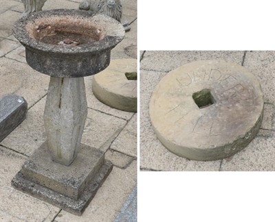 Lot 1107 - A weathered composition pedestal birdbath; together with a stone mill wheel inscribed 'Under Fell'