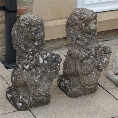 Lot 1110 - A pair of weathered concrete seated lions bearing shields