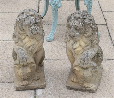 Lot 1113 - A pair of weathered composition seated lions bearing shields
