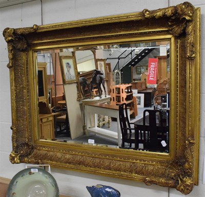 Lot 1173 - An ornate gilt and carved mirror with rectangular bevelled plate, 89cm high by 120cm wide