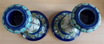 Lot 2004 - A Pair of Burmantofts Faience Pottery Candlesticks, decorated with flower heads in blues and...