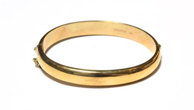 Lot 525 - A 9 carat gold hinged bangle, with floral engraved detail to the upper section