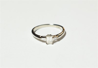 Lot 603 - A platinum diamond solitaire ring, the emerald-cut diamond in a claw setting, to tapered...