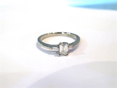 Lot 603 - A platinum diamond solitaire ring, the emerald-cut diamond in a claw setting, to tapered...