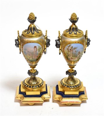 Lot 789 - A pair of Continental porcelain and gilt metal mounted urns painted with vignettes and twin...