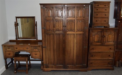 Lot 1151 - A reproduction oak five piece linen fold bedroom suite comprising: wardrobe, bedside chest,...