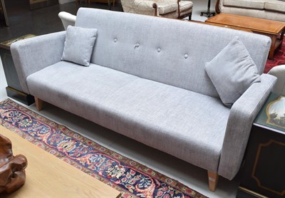 Lot 1159 - A modern three-seater sofa covered in grey fabric with beech legs