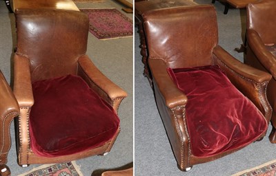 Lot 1191 - A pair of early 20th century club armchairs, upholstered in brown close-nailed leather