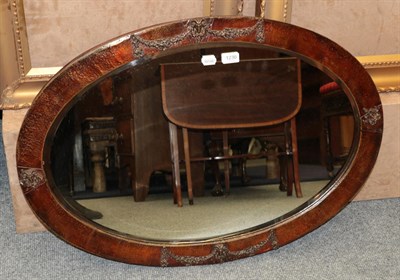 Lot 1230 - An oval copper framed mirror decorated with rams heads and swags, together with an oval...