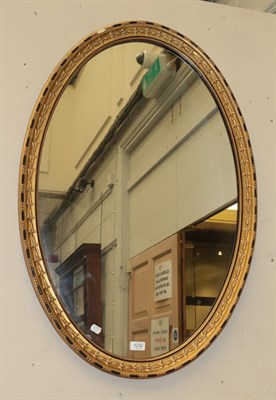 Lot 1232 - An early 20th century gilt and gesso oval mirror, the frame decorated with husks