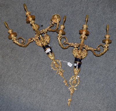 Lot 1303 - A pair of impressive three-light gilt-metal wall sconces, each issuing three leaf-cast arms...